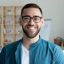 Close up headshot portrait of smiling young Caucasian businessman in glasses posing in office. Profile picture of happy millennial male employee or worker in eyewear at workplace. Employment concept.